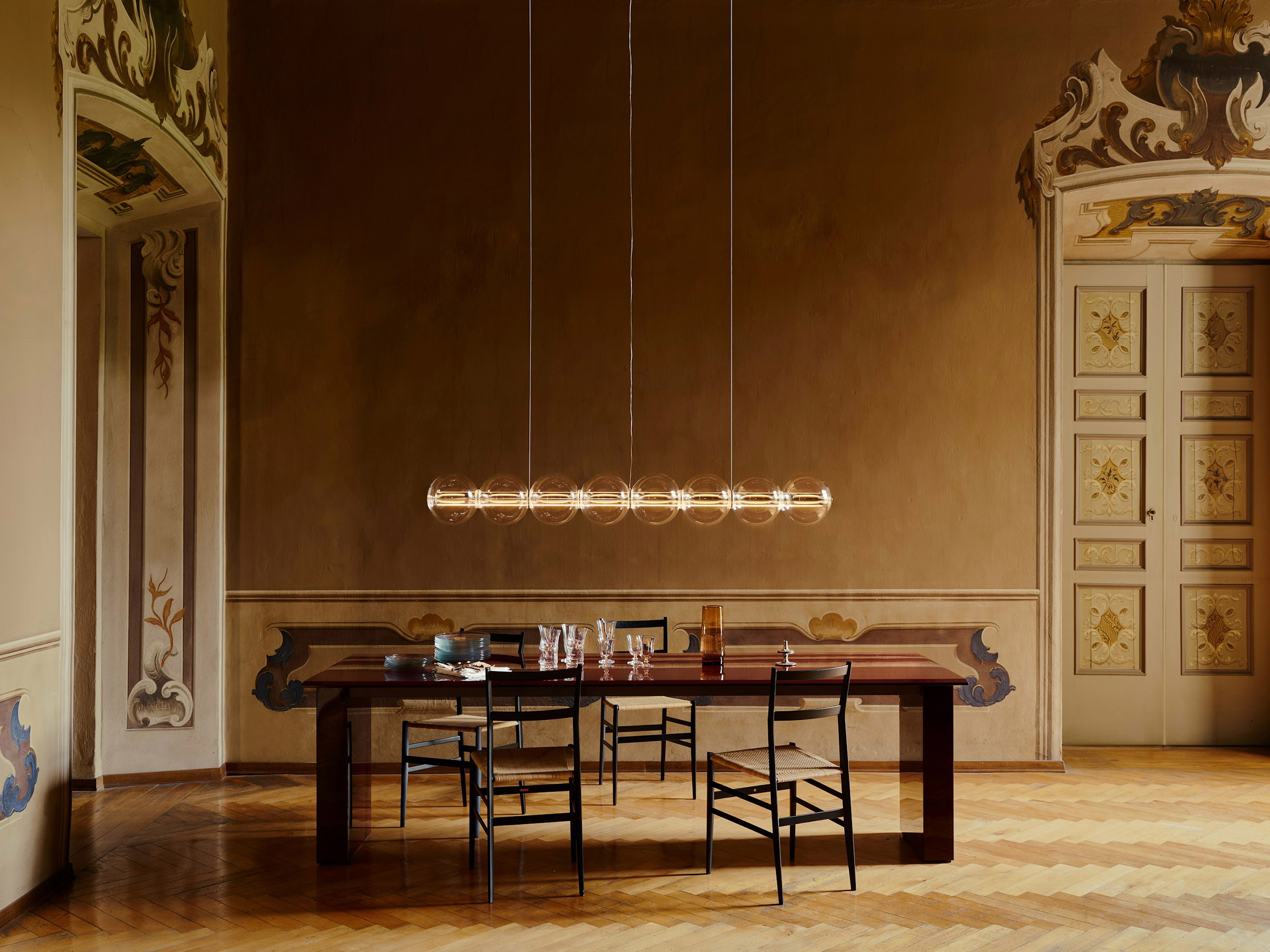FLOS Luce Sferica suspended over a dining table, showcasing its ambient glow